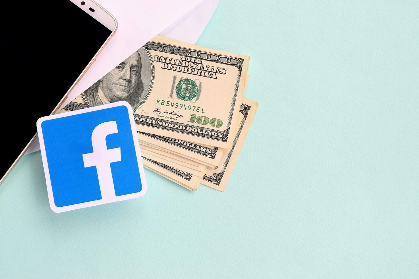 Facebook Paper Logo Lies With Envelope Full of Dollar Bills and Smartphone Free Photo