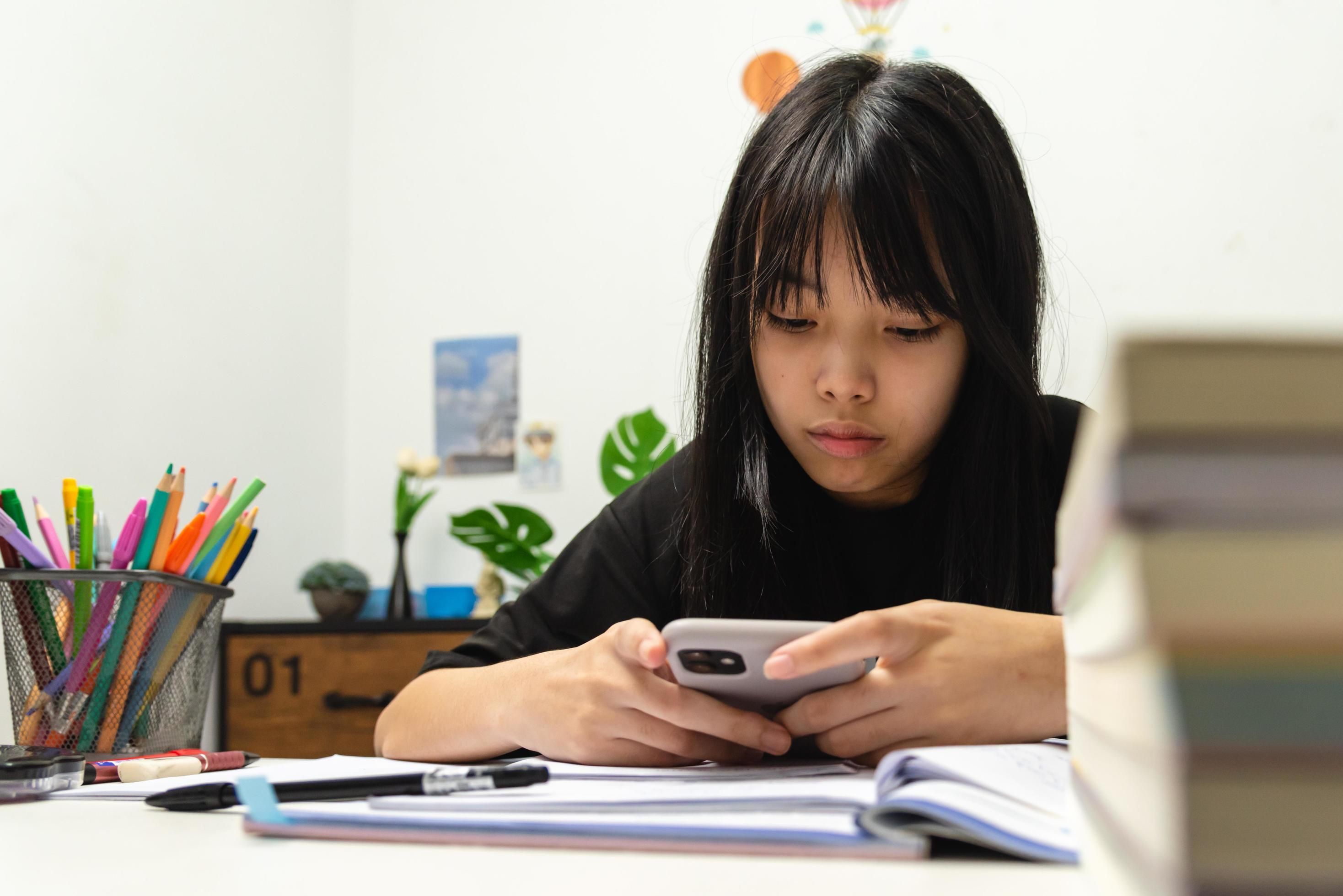 Asian Young Girl Use a Mobile Smart Phone to Study Education Online at Home Free Photo